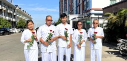 5 youth environmental human rights defenders dressed in white holding two red roses stand in the middle of an empty street. Credit: Mother Nature Cambodia