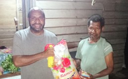 Photo of Agustinus Mahuze with food donations giving to community member. Credit: Agustinus Mahuze
