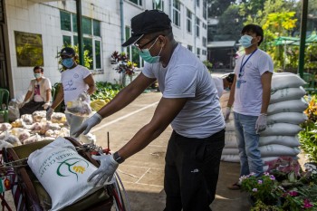 A member of the “Public to Public” charity group puts a bag of rice on a trishaw at a COVID-19 donation event in Yangon in April 2020. (Frontier)