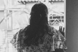 Photo of a woman in Sri Lanka looking out a window with her back turned. Credit: UN Photo